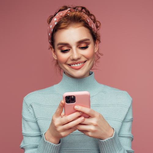 smiling woman holding a pink phone