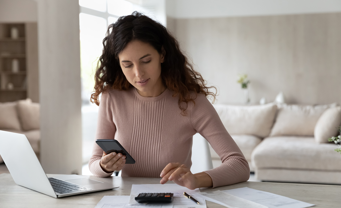 woman using calculator while on phone